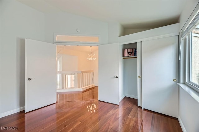 unfurnished bedroom featuring lofted ceiling, dark wood-type flooring, and a closet