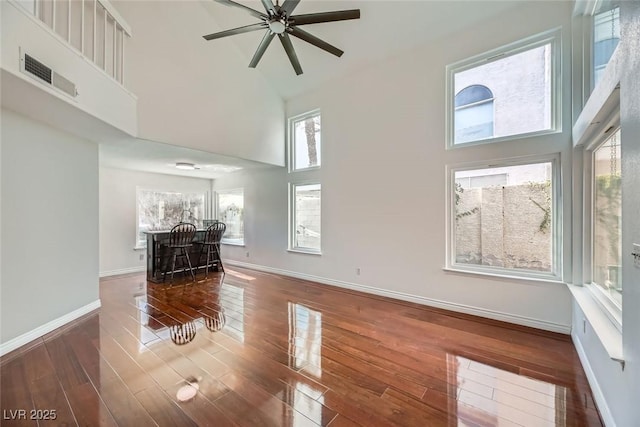 unfurnished living room featuring ceiling fan and a high ceiling