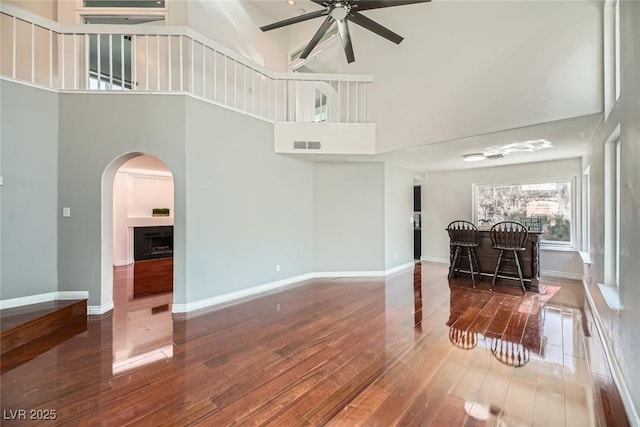 living room with a towering ceiling, ceiling fan, and hardwood / wood-style flooring