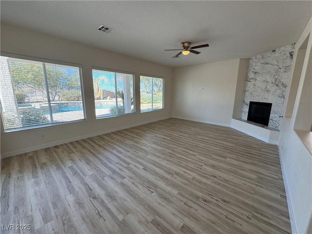 unfurnished living room with ceiling fan, a fireplace, and light hardwood / wood-style floors