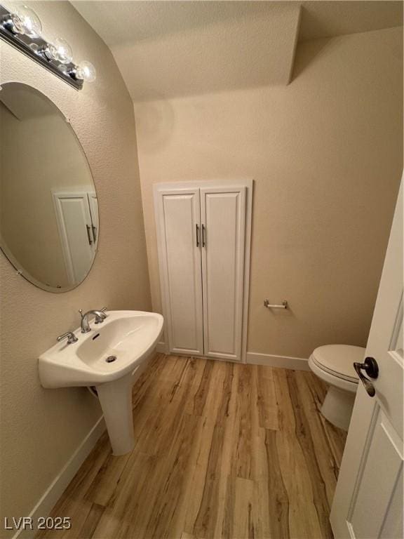 bathroom with lofted ceiling, wood-type flooring, and toilet