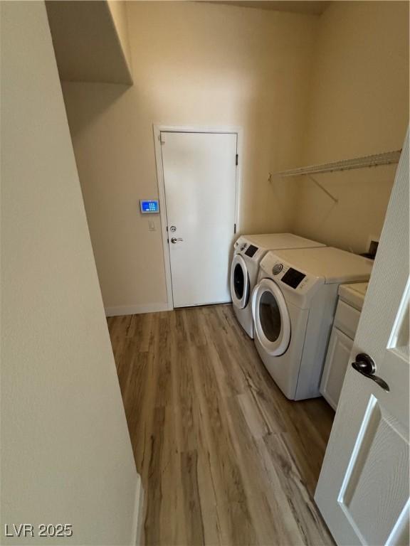 washroom with washer and dryer, cabinets, and light wood-type flooring