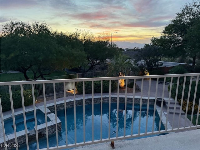 pool at dusk with an in ground hot tub