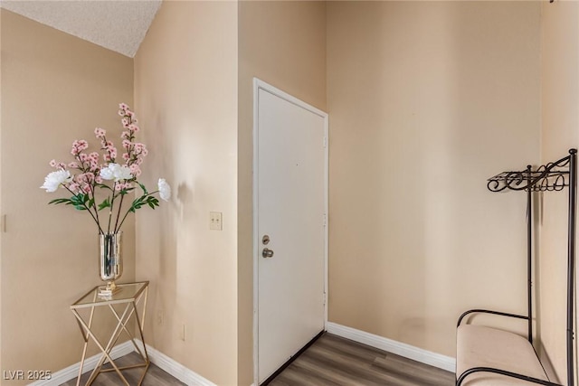 interior space with a textured ceiling, wood finished floors, and baseboards