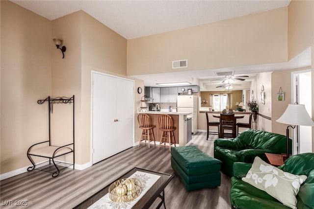 living room with hardwood / wood-style floors, ceiling fan, and a high ceiling