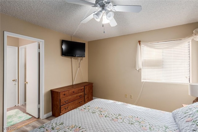 bedroom with a ceiling fan, a textured ceiling, and wood finished floors