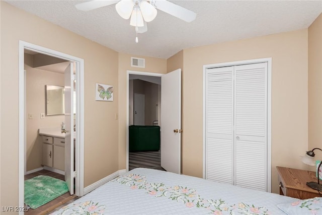 bedroom with ceiling fan, connected bathroom, a closet, and a textured ceiling