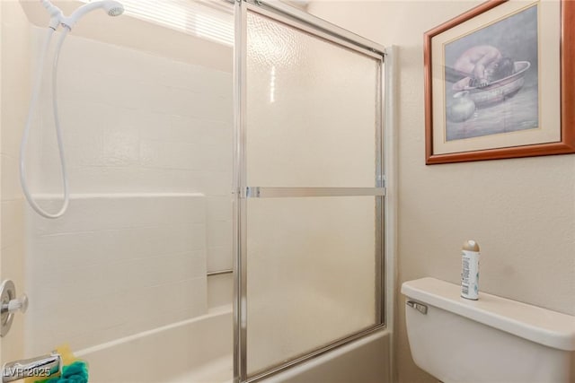 bathroom with toilet and bath / shower combo with glass door