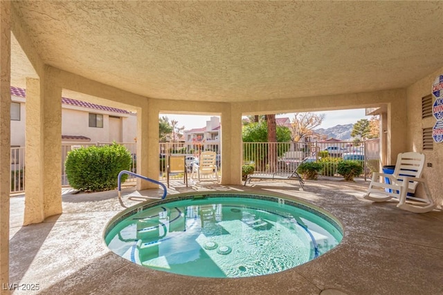 view of pool with a community hot tub, a patio area, and fence