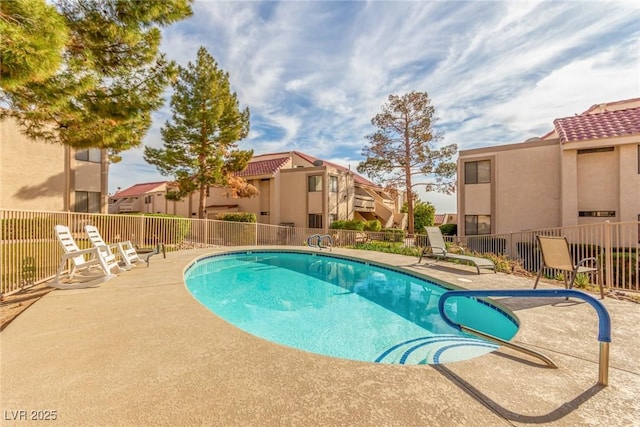 pool with a patio, fence, and a residential view