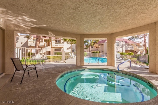 view of pool with a community hot tub, a patio area, and fence