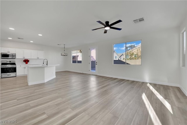 unfurnished living room featuring sink, ceiling fan with notable chandelier, and light hardwood / wood-style flooring