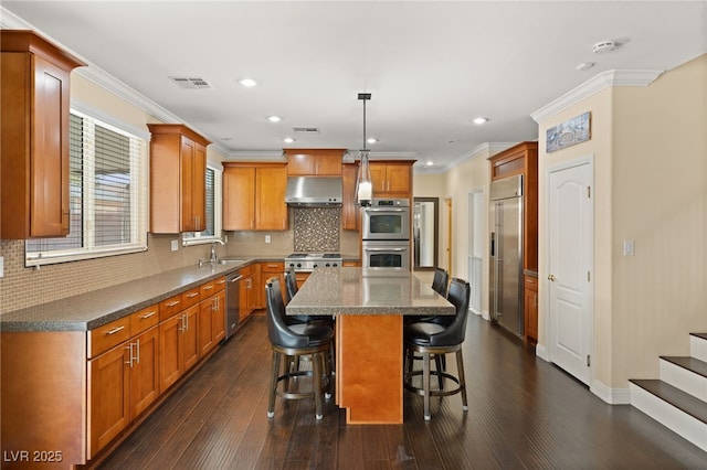 kitchen featuring pendant lighting, sink, a center island, stainless steel appliances, and dark wood-type flooring