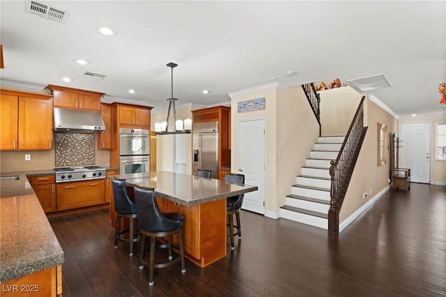 kitchen with a kitchen island, appliances with stainless steel finishes, decorative light fixtures, range hood, and crown molding