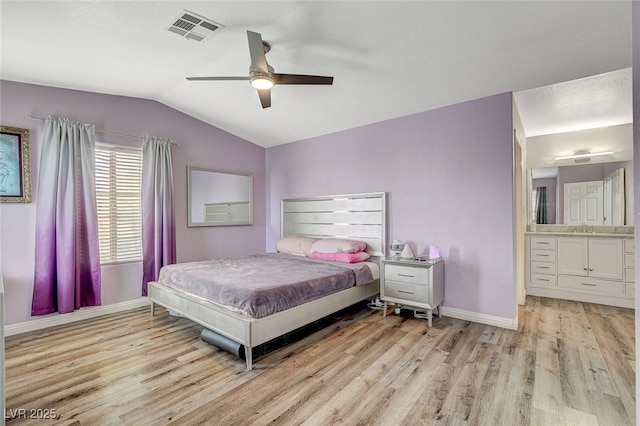 bedroom featuring lofted ceiling, sink, ceiling fan, light hardwood / wood-style floors, and ensuite bath