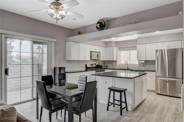 kitchen featuring sink, white cabinetry, a center island, stainless steel appliances, and backsplash