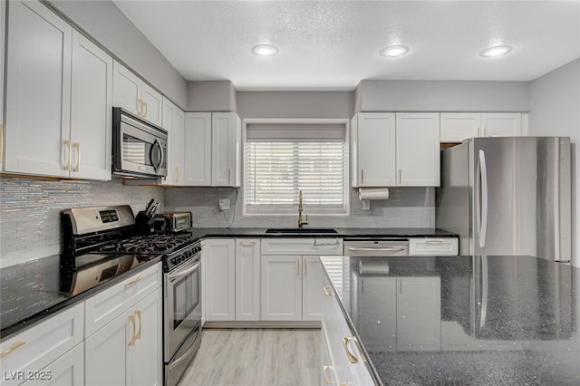 kitchen featuring white cabinetry, sink, dark stone counters, and appliances with stainless steel finishes