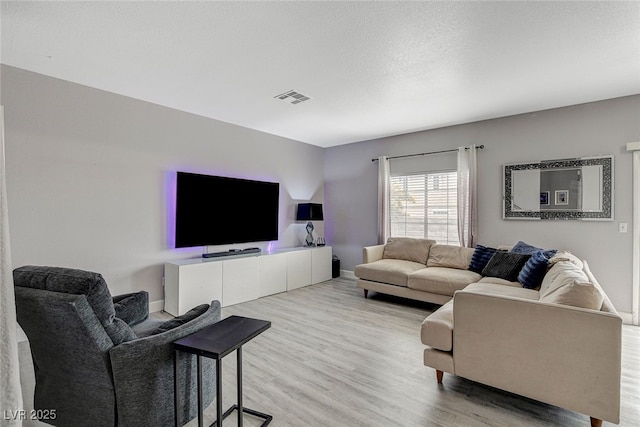 living room with a textured ceiling and light hardwood / wood-style flooring