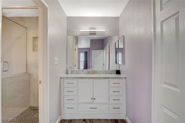 bathroom featuring hardwood / wood-style flooring, vanity, and walk in shower