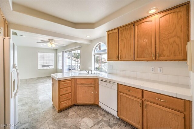 kitchen featuring sink, white appliances, tile counters, kitchen peninsula, and ceiling fan