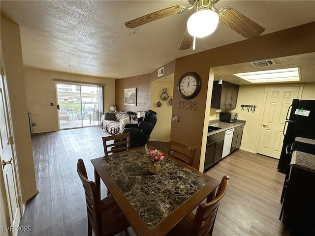 dining space with ceiling fan, a textured ceiling, and light hardwood / wood-style flooring