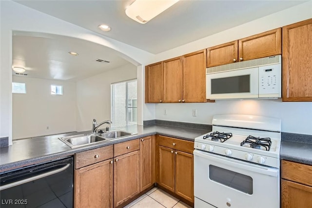 kitchen featuring sink, white appliances, light tile patterned floors, and kitchen peninsula