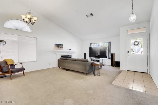 living room with high vaulted ceiling, a fireplace, light colored carpet, and a chandelier