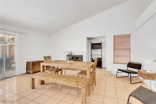 tiled dining room featuring lofted ceiling and a tile fireplace