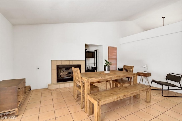 dining room featuring lofted ceiling, a tile fireplace, and light tile patterned floors