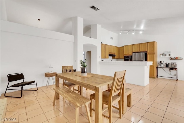 tiled dining area featuring high vaulted ceiling