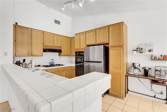 kitchen with sink, tile countertops, stainless steel appliances, and vaulted ceiling