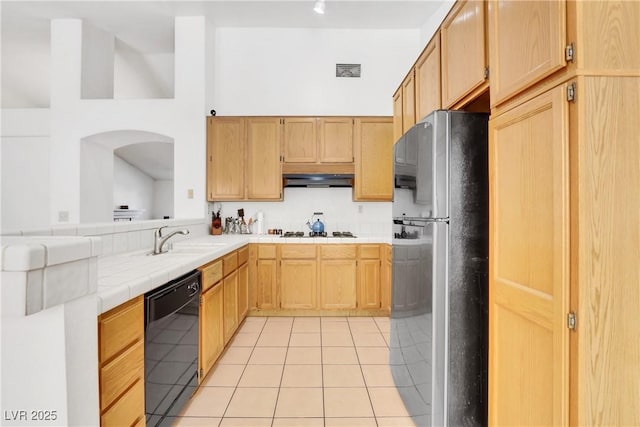 kitchen featuring light tile patterned flooring, tile countertops, stainless steel refrigerator, dishwasher, and sink