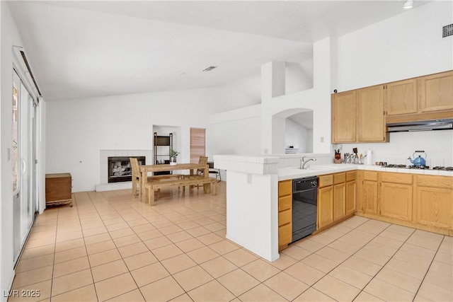 kitchen featuring black dishwasher, a tiled fireplace, light tile patterned floors, kitchen peninsula, and gas stovetop