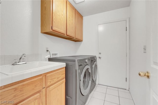 laundry room with cabinets, sink, light tile patterned floors, and washer and clothes dryer