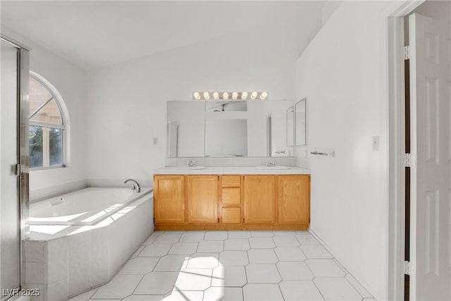 bathroom featuring vanity, a relaxing tiled tub, and lofted ceiling