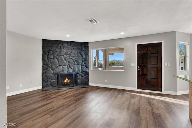 unfurnished living room featuring a stone fireplace and hardwood / wood-style floors