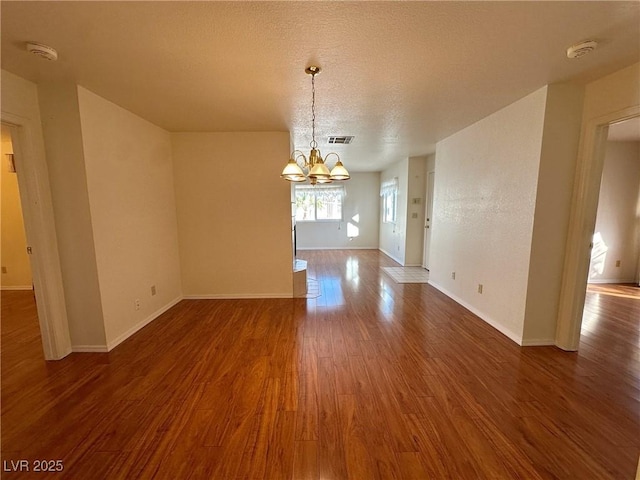 interior space with dark wood-type flooring, a chandelier, and a textured ceiling