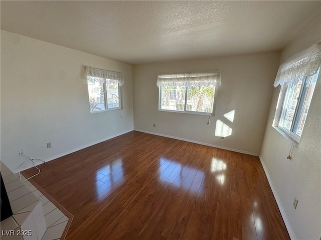 unfurnished room with hardwood / wood-style flooring and a textured ceiling