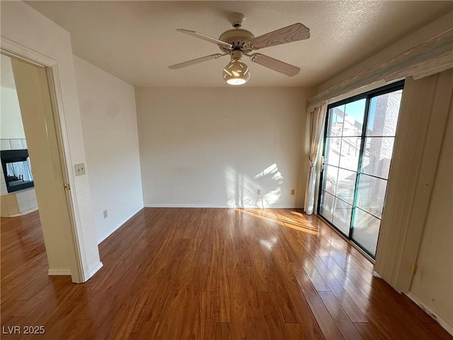 spare room featuring ceiling fan, a textured ceiling, a fireplace, and wood-type flooring