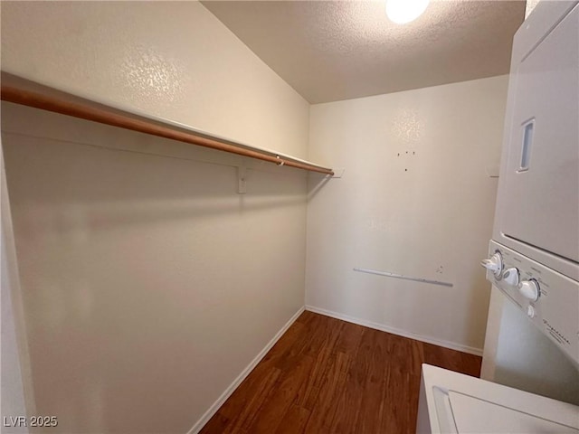 spacious closet featuring stacked washing maching and dryer and dark hardwood / wood-style flooring