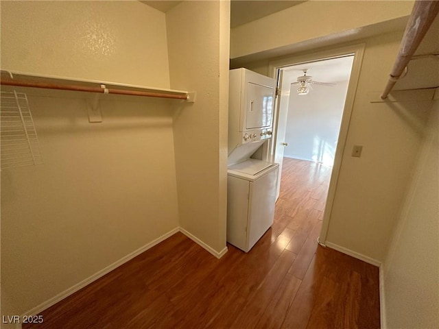 walk in closet featuring hardwood / wood-style flooring, stacked washer / drying machine, and ceiling fan