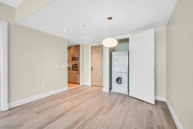 interior space with stacked washer / drying machine and light hardwood / wood-style flooring