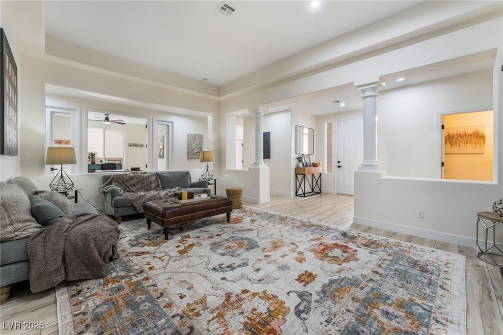 living room with decorative columns, ceiling fan, and light hardwood / wood-style floors