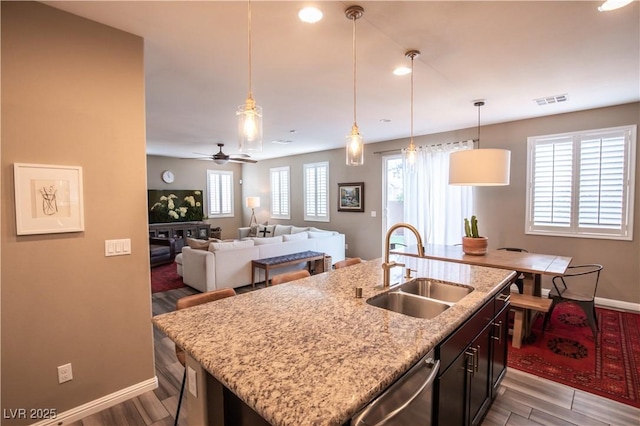 kitchen featuring stainless steel dishwasher, pendant lighting, sink, and a center island with sink