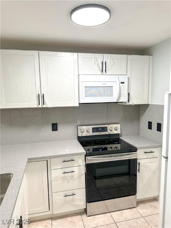 kitchen featuring white cabinetry, white appliances, tasteful backsplash, and light tile patterned floors