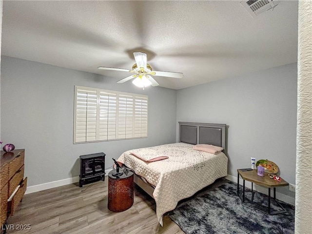 bedroom featuring a textured ceiling, wood-type flooring, and ceiling fan