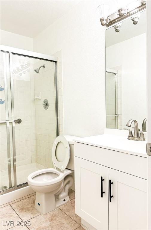 bathroom with tile patterned flooring, vanity, a shower with shower door, and toilet