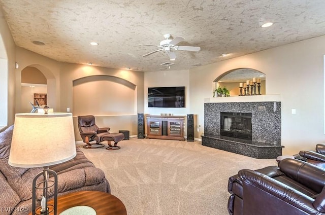 living room featuring carpet, a high end fireplace, a textured ceiling, and ceiling fan