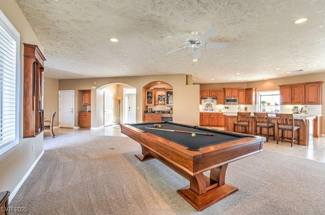 game room featuring a textured ceiling, pool table, light colored carpet, and ceiling fan