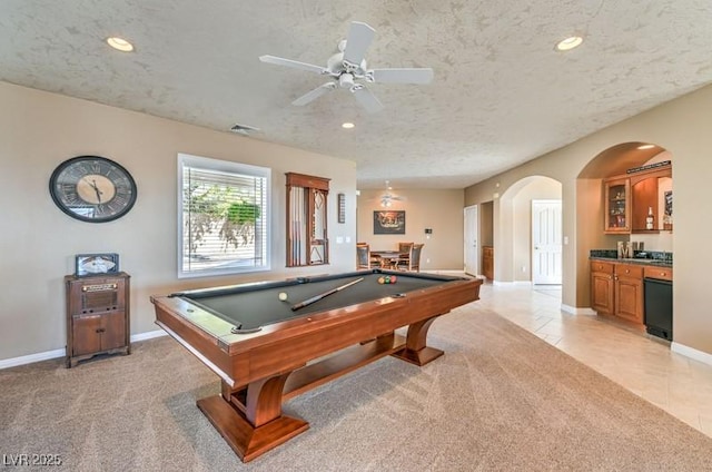 playroom with pool table, a textured ceiling, ceiling fan, bar area, and light colored carpet